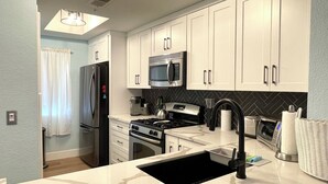A modern kitchen with white cabinets, stainless steel appliances, and a black sink.