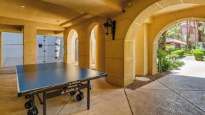 A ping pong table in a corridor with arches and an exit sign.