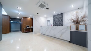 A modern reception area with a marble counter, a computer on a cart, and a decorative plant. - Jeonju Hotel Davin (Jeonju)