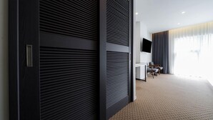 A modern hotel room with a large sliding door, a flat-screen TV mounted on the wall, a seating area with a small table, and a large window with curtains. - Jeonju Hotel Davin (Jeonju)