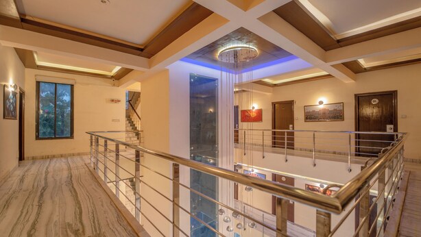 Un interior espaiós amb un sostre alt, un candelabrum central i una escala que mena a un nivell superior.