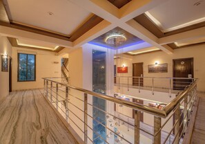 A spacious interior with a high ceiling, a central chandelier, and a staircase leading to an upper level. - Hotel Royal Primes (Jaipur)