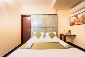 A hotel room with a bed, a headboard, a nightstand, and a wall-mounted air conditioner. - Hotel Royal Primes (Jaipur)