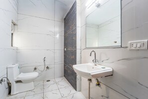 A bathroom with a toilet, sink, and mirror. - Hotel Royal Primes (Jaipur)