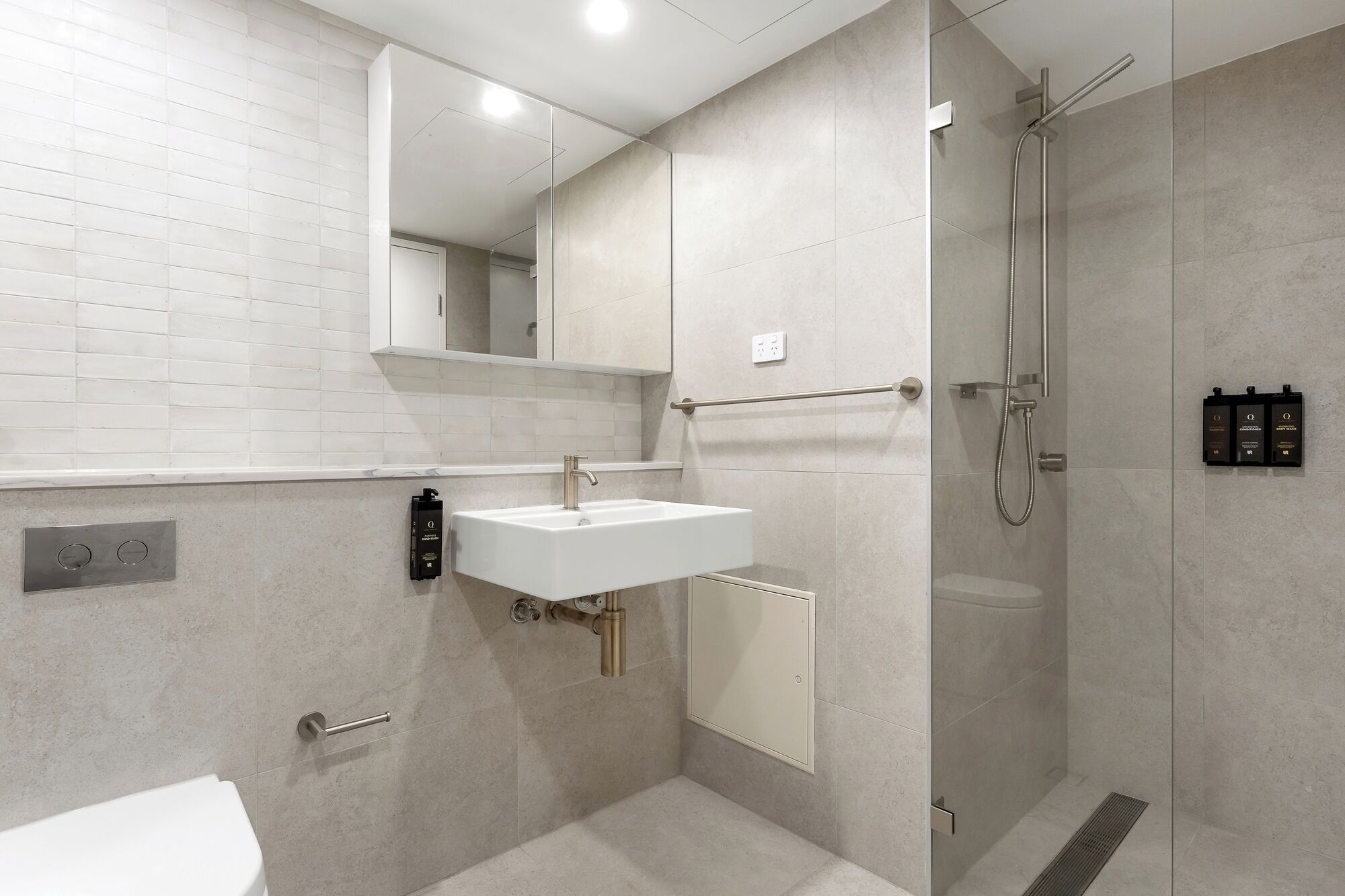 Ein modernes Badezimmer mit einem weißen Waschbecken, einer Glasdusche und einem Spiegel über dem Waschbecken.