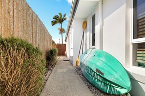 Guests can access the property via a narrow pathway lined with a hedge and a wooden fence.