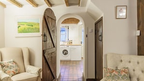 A hallway with a wooden door, a chair, and a couch. - Honeypot Cottage-Lovely Bolthole in Stow (Cheltenham)
