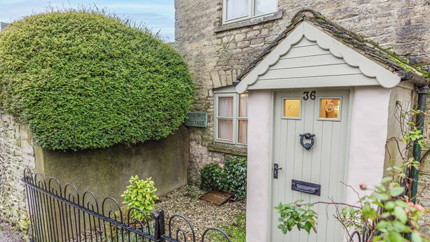 A cottage with a stone wall, a metal fence, and a door marked with the number 36. - Honeypot Cottage-Lovely Bolthole in Stow (Cheltenham)