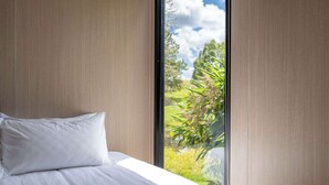 Een slaapkamer met een groot raam, een bed en uitzicht op groen.