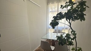 Una habitación pequeña y luminosa con suelo de madera en espiga, una mesa de cristal y dos sillas.