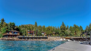 A waterfront property with a wooden deck, a stone pier, and a view of a forested hillside. - Kings Beach Escape w/ Patio & Pool Access (Kings Beach)