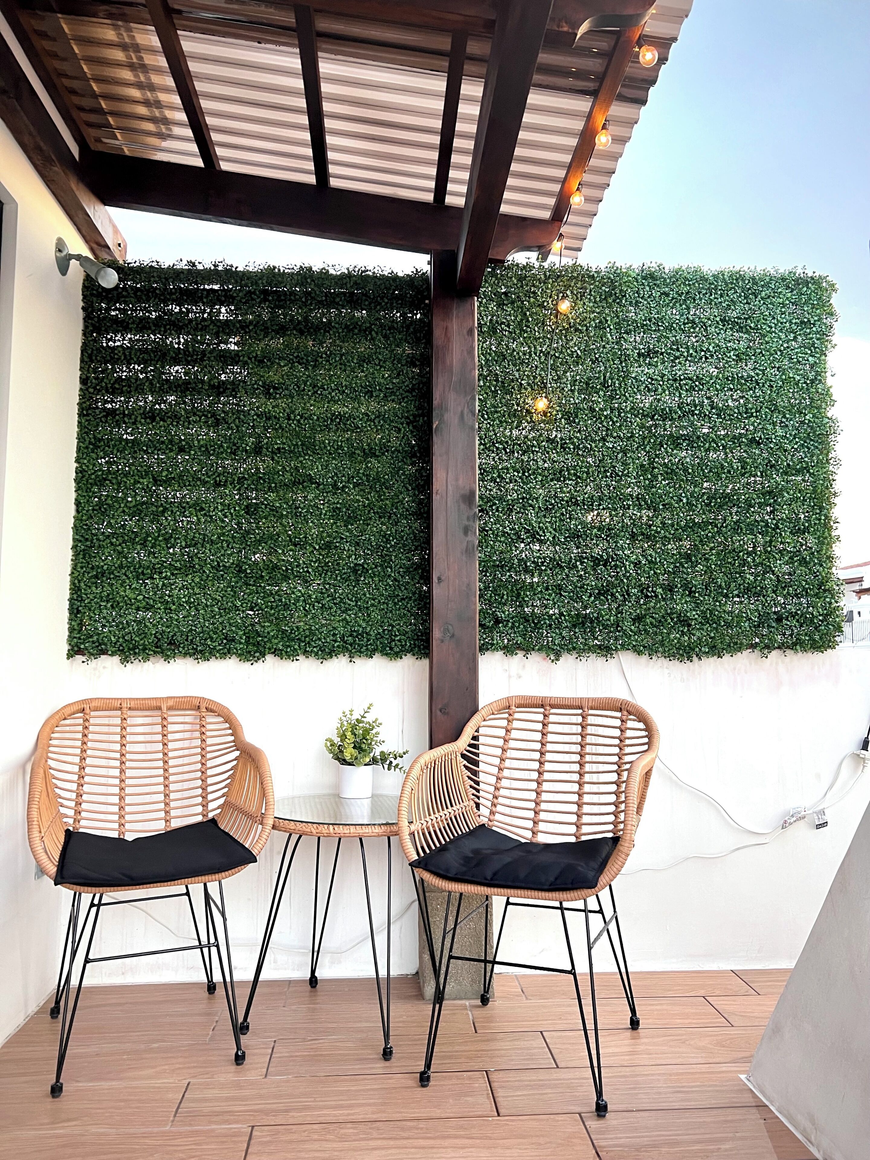 Une terrasse avec deux fauteuils en osier, une petite table et une plante en pot.