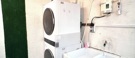 A laundry room with a large industrial washer, a sink, and a sign indicating the room's purpose.