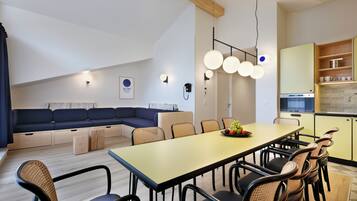 A modern kitchen with a dining area, wooden ceiling beams, and a built-in seating area.