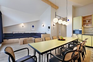Une cuisine moderne avec un coin repas, des poutres apparentes en bois au plafond et un espace salon intégré.