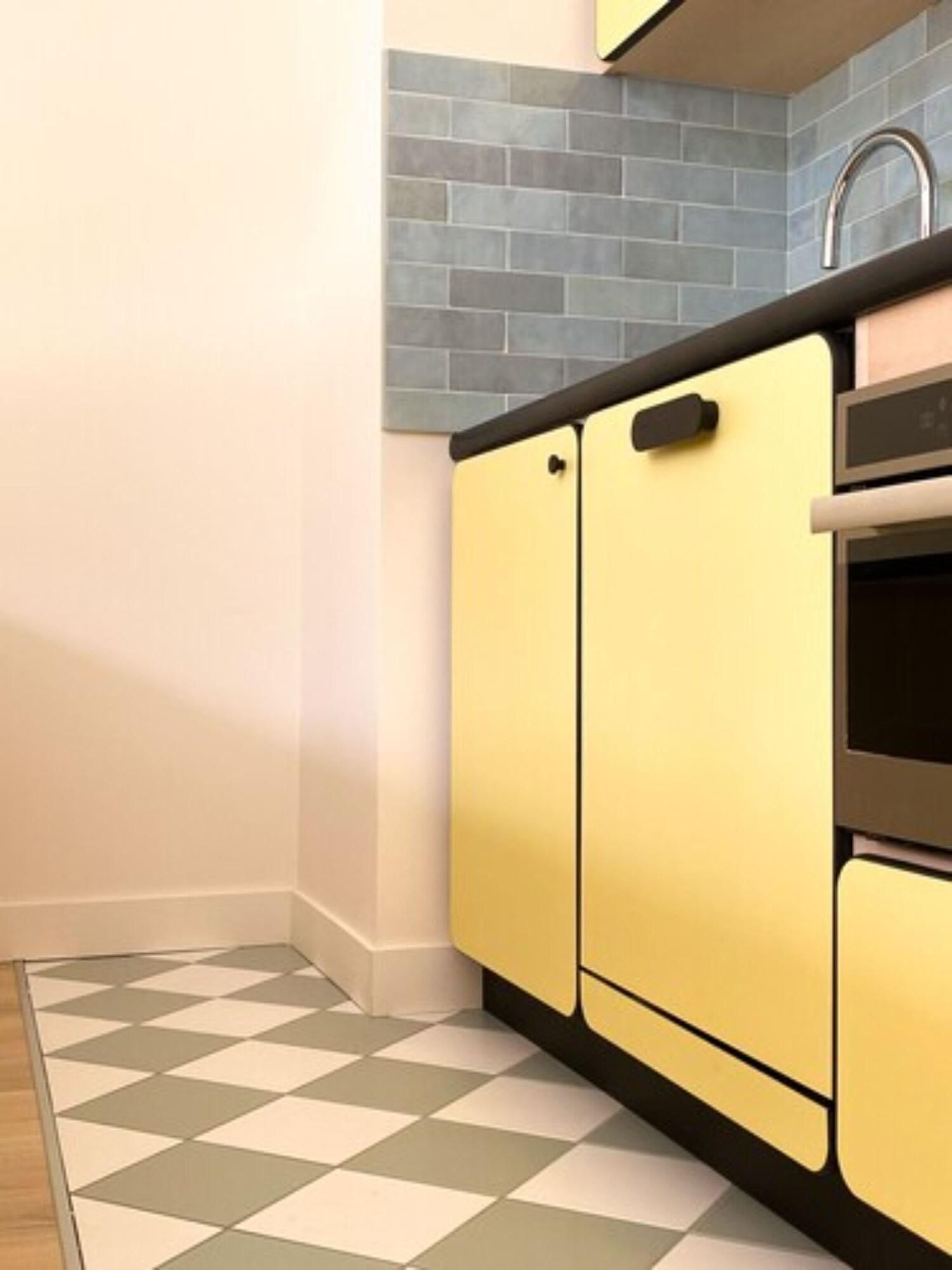 A kitchen with yellow cabinets, a black countertop, and a tiled backsplash.