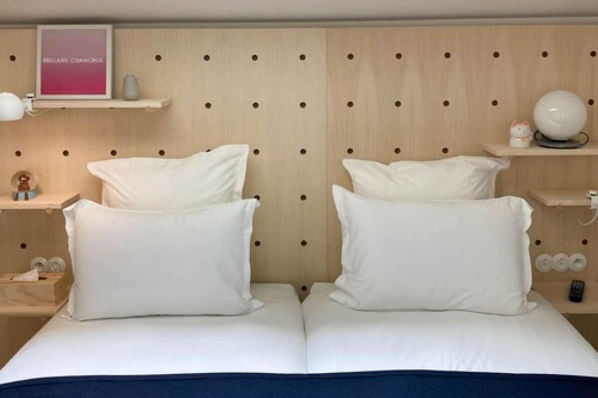 A double bed with white bedding and a wooden headboard with circular cutouts.