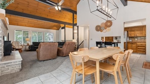 Un vaste espace de vie comprenant une salle à manger avec une table en bois, des sièges confortables et une cuisine dotée de meubles en bois.