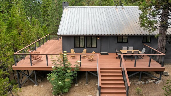 A modern cabin with a deck, outdoor seating, and a staircase.
