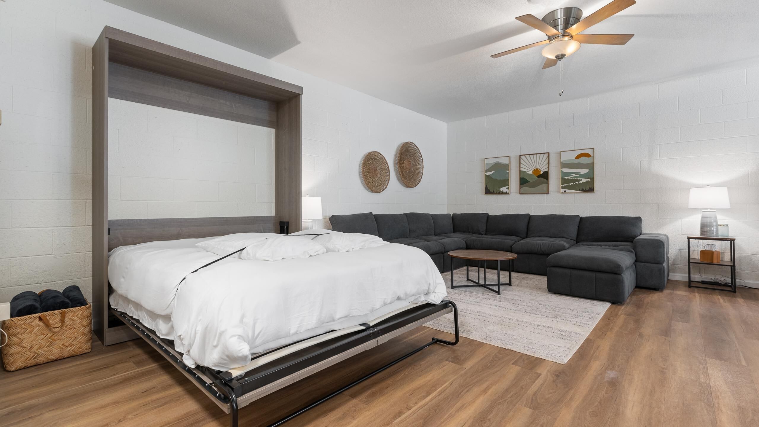 Un dormitorio moderno con cama, sofá, mesa de centro y ventilador de techo.