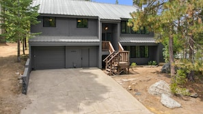 Une maison à deux étages avec un garage, un escalier en bois et une allée en béton.