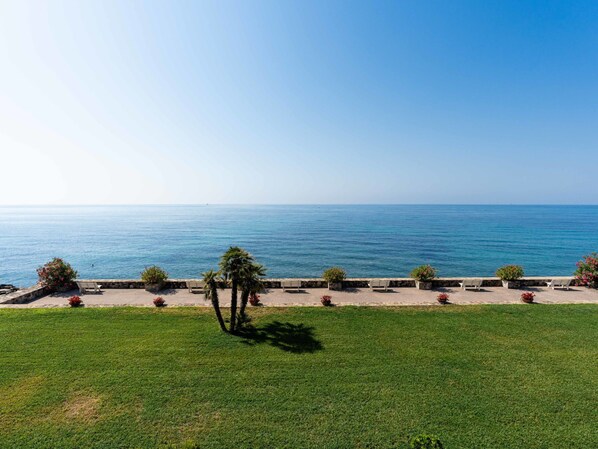 A coastal view with a grassy area, benches, and potted plants along a stone wall. - Loggia sul mare by Interhome (Ventimiglia)