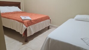 Ett hotellrum med två sängar, den ena med ett orange överkast och den andra med ett vitt överkast.