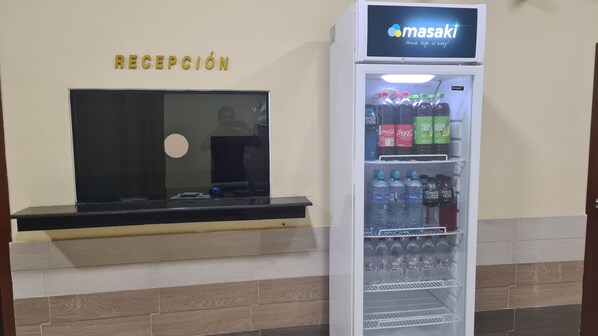 Un'area reception con un frigorifero fornito di bevande e uno schermo televisivo.