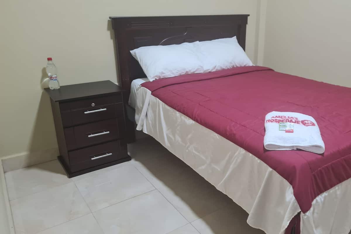 Una cama bien hecha con una colcha blanca y granate, una almohada blanca y una toalla blanca doblada con texto.