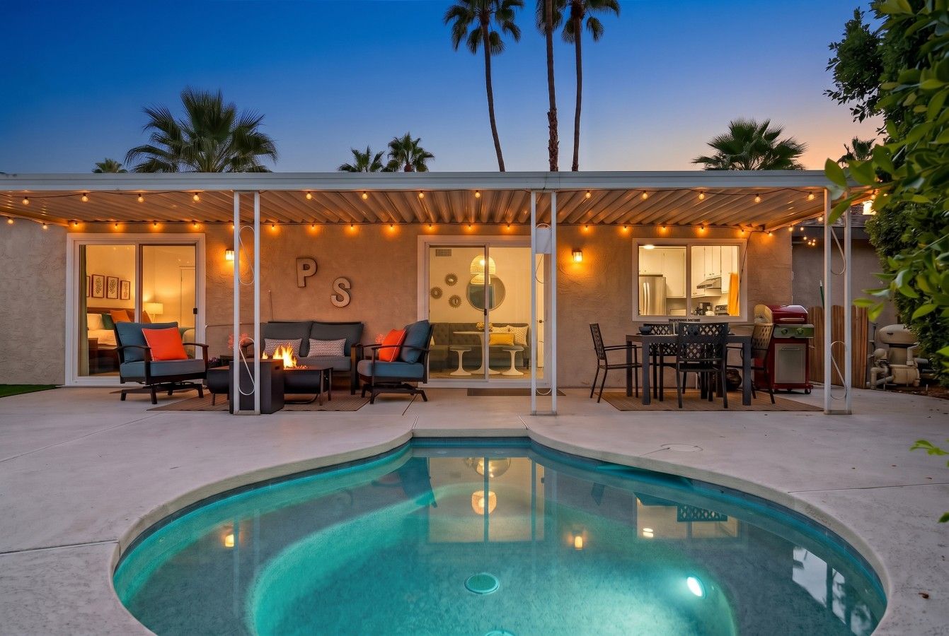 A modern house with a swimming pool, outdoor seating, and a covered patio area.
