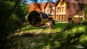 A rustic wooden cabin with a large barrel in the foreground, surrounded by lush greenery. - Logis Hotel Le Chalet Altitude (Pierre-Percée)