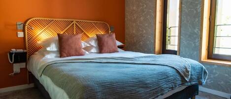 A bed with a geometric headboard, two pillows, and a blue blanket.