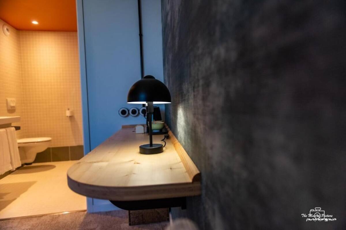 A bathroom with a wooden vanity, a black lamp, and a towel rack.