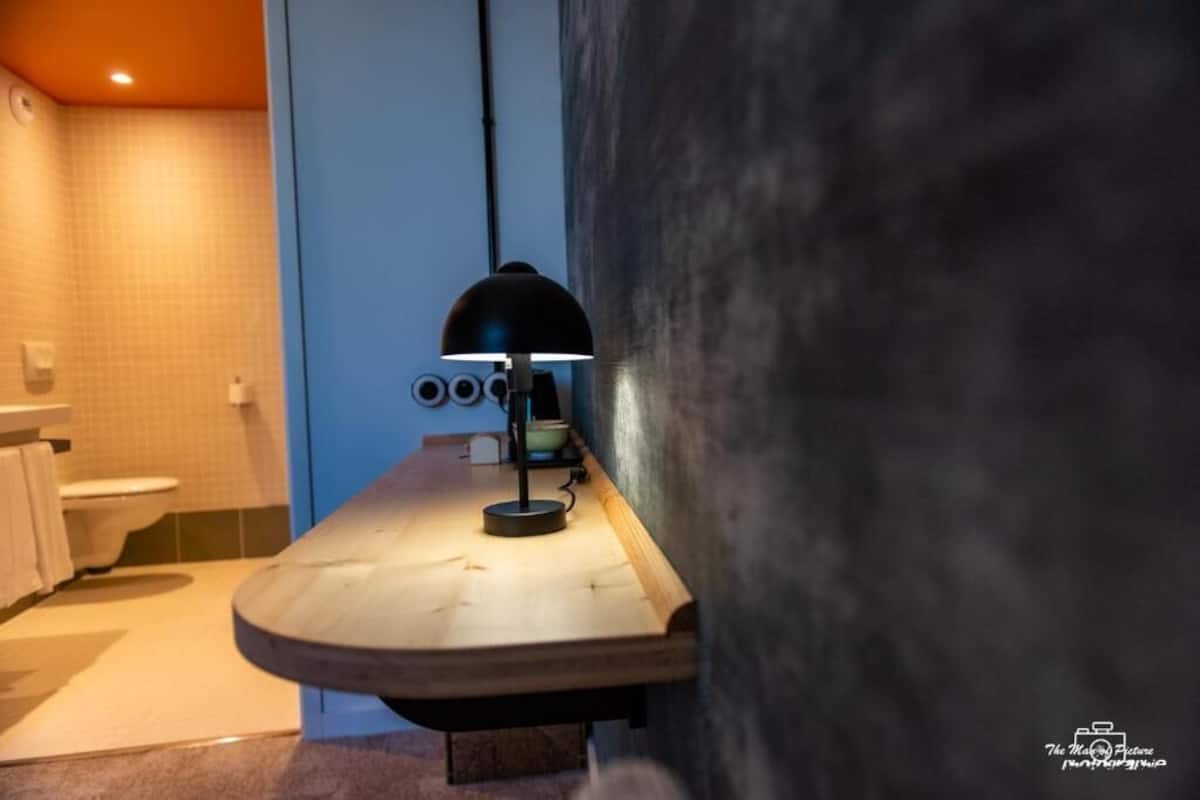 Une salle de bain avec un meuble-lavabo en bois, une lampe noire et un porte-serviettes.