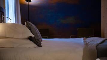 A hotel room with a bed, pillows, a bedside lamp, and a wall mural.