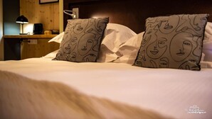 A hotel room with a wooden headboard, white bedding, and patterned pillows. - Logis Hotel Le Chalet Altitude (Pierre-Percée)