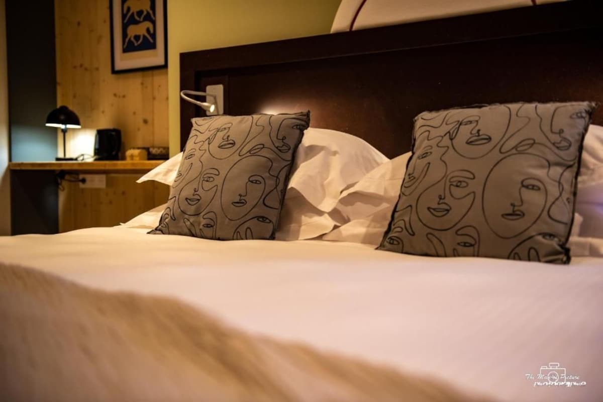 A hotel room with a wooden headboard, white bedding, and patterned pillows.