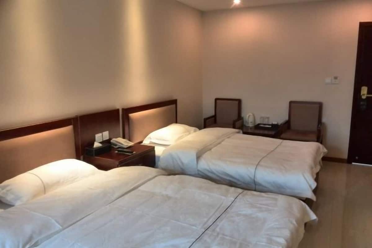 Hotellihuone, jossa on kaksi sänkyä, yöpöytä, jossa on puhelin, ja kaksi tuolia.
