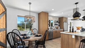 Une cuisine moderne dotée d’un îlot central, de meubles en bois et d’un coin repas avec des chaises noires et une table ronde.