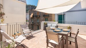Terraço com mesa posta para refeições, cadeiras de lounge e um amplo toldo branco.