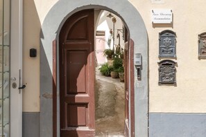 Un arco che conduce a un stretto sentiero con una porta in legno. Un cartello sopra la porta recita "Ture Charming Accommodation".
