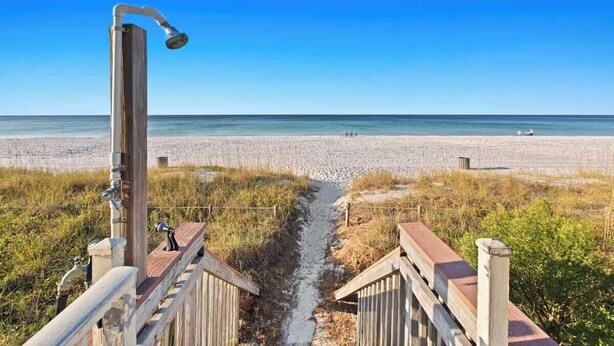 A beach pathway leading to a wooden structure with a showerhead, overlooking a sandy beach and ocean. - Latitude 29 Unit 19 (Panama City Beach)