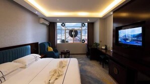 Een hotelkamer met een bed, een televisie, een bureau en een raam met uitzicht op de stad.