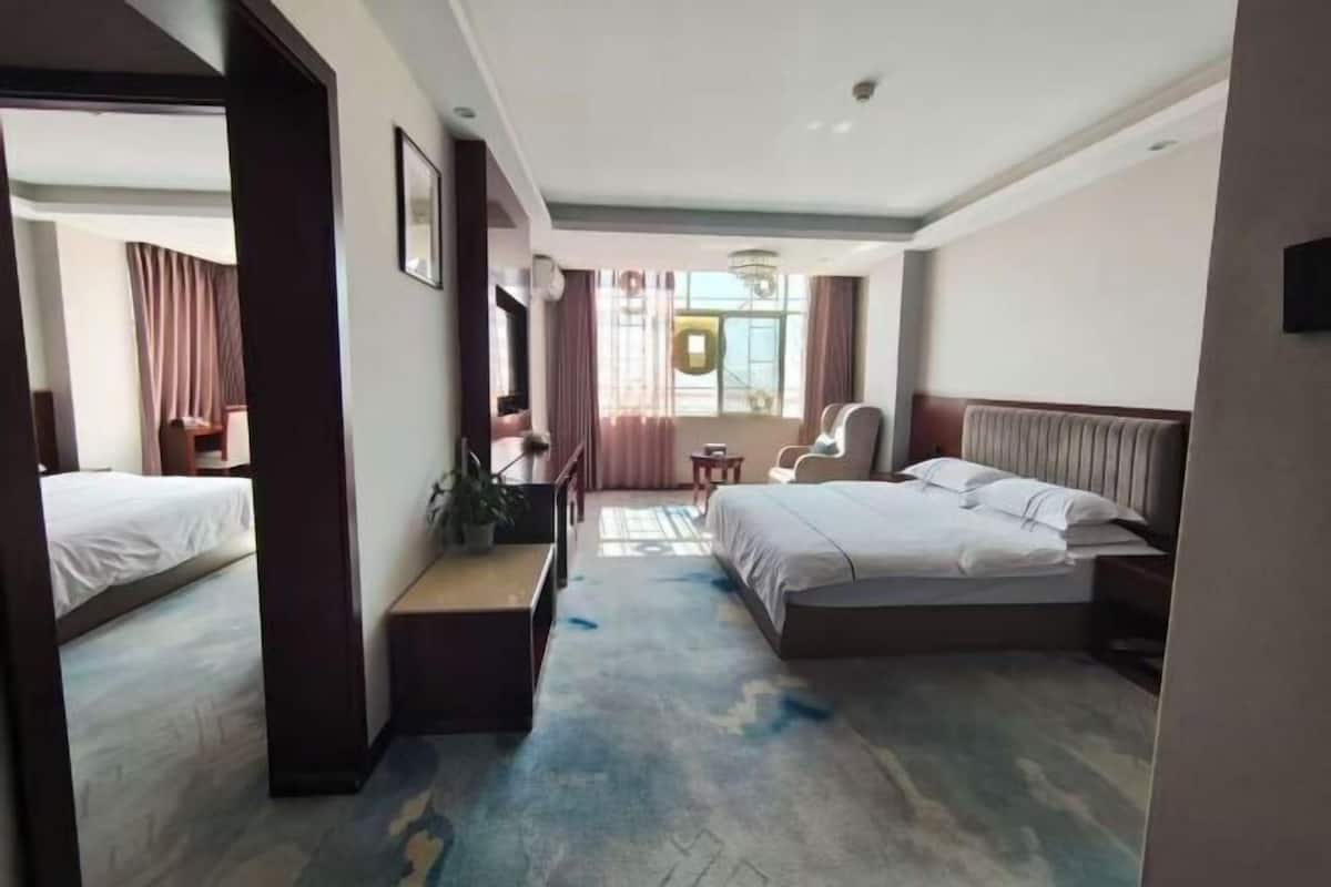 A hotel room with a bed, a desk, a chair, a TV, and a window with curtains.