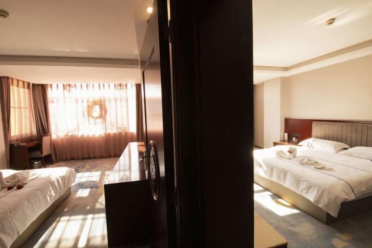 A hotel room with two beds, a desk, and a large mirror.