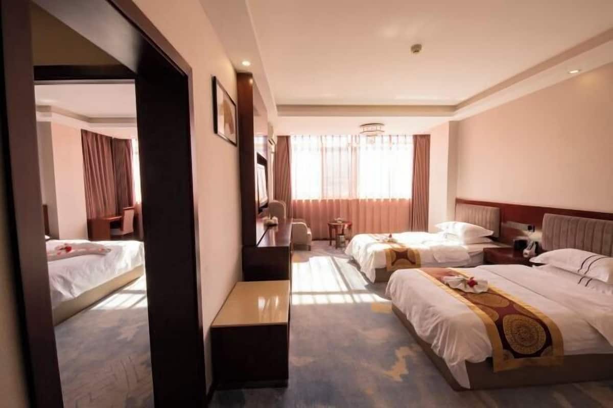 A hotel room with two beds, a desk, a chair, a small table, and a mirror.