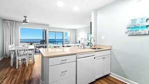 A modern kitchen with a large island, white cabinetry, and a view of the ocean.