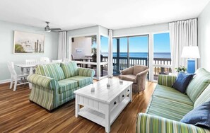 A living room with striped sofas, a white coffee table, and a view of the ocean. - Latitude 29 Unit 20 (Panama City Beach)