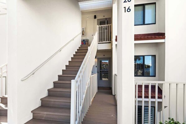 A staircase with white railings and a wooden handrail leading to a door marked with the number 20. - Latitude 29 Unit 20 (Panama City Beach)