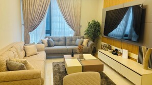 Un salon moderne avec un canapé, des fauteuils, une table basse et un téléviseur.